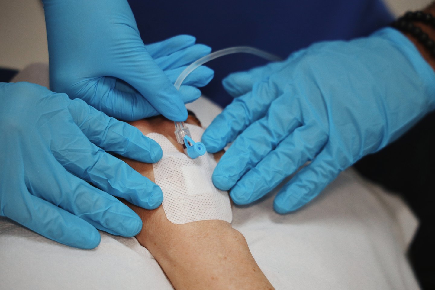 Gloved hands preparing an intravenous line in clinic